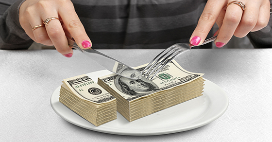 woman with knife and fork cutting stack of money in half